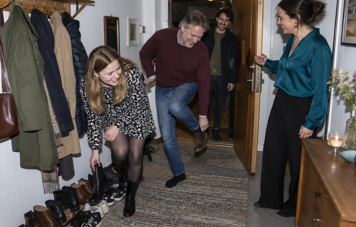 Gäster tar av sig skorna i en full hall när de kommer till ett kalas